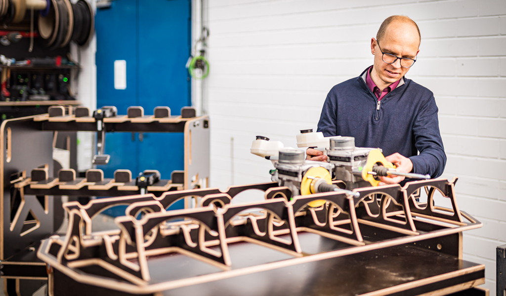 The image shows a man putting parts into wooden load carriers.