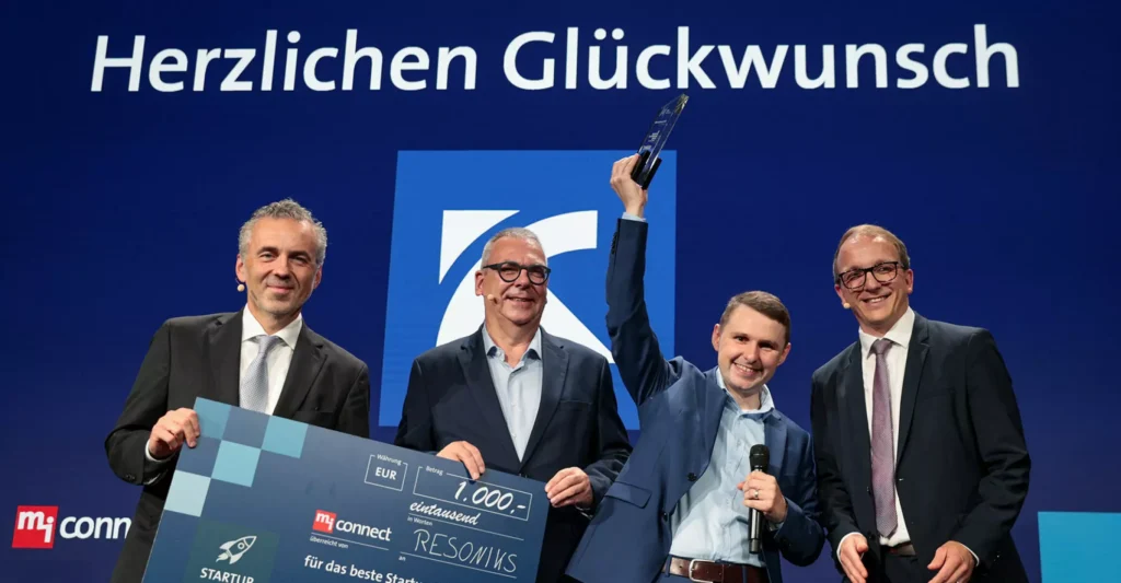 This picture show the Fabian Oberndorfer on stage of Maschinenbaugipfel and three other men who congratulate him on the win of the VDMA startup award.